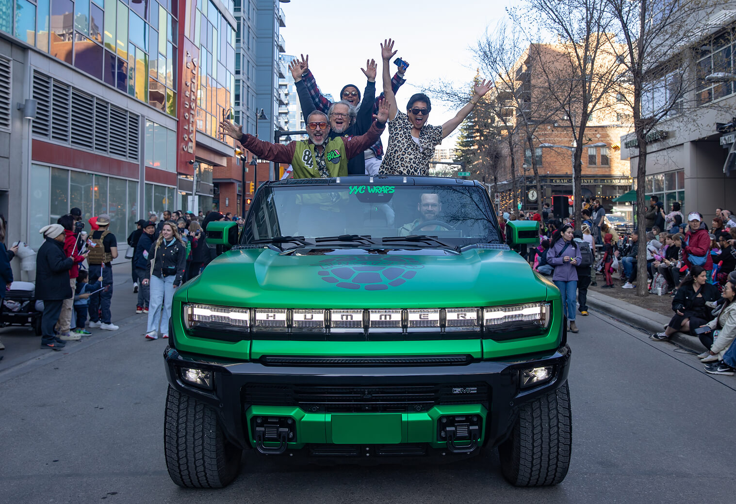 The green YYC Wraps Hummer EV carrying the Teenage Mutant Ninja Turtles cast down a packed downtown Calgary street during the Calgary Expo Parade of Wonders